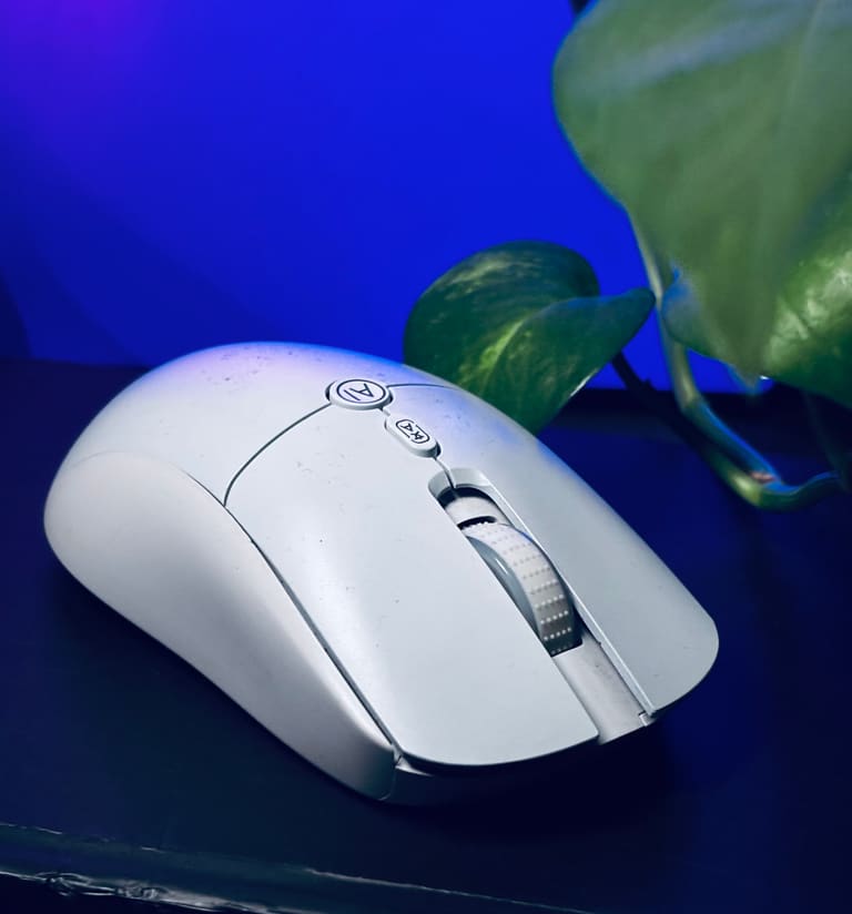 Aitroneecs AI Smart Voice Mouse on a desk next to a plant, lit in blue